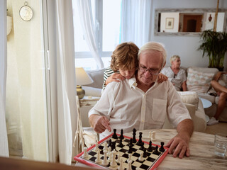 Loving grandson spending weekend with grandparents and playing chess