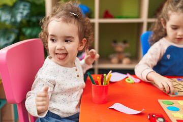 Adorable girls playing with maths puzzle game sitting on table at kindergarten