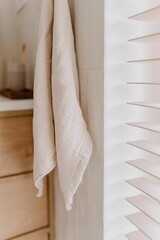 Fototapeta premium White towel hangs from a corner in a sunlit bathroom, near a window