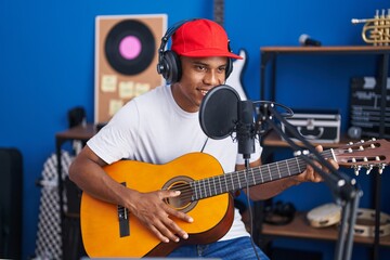 Young latin man musician singing song playing classical guitar at music studio