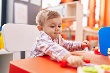 Adorable caucasian boy smiling confident sitting on table at kindergarten