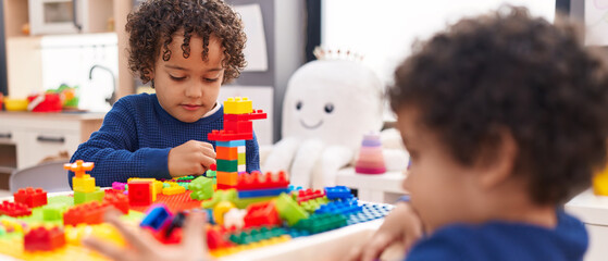 Adorable african american boys playing with construction blocks sitting on table at kindergarten © Krakenimages.com