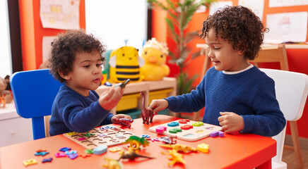 Adorable african american boys playing with maths puzzle game and dinosaur toy at kindergarten