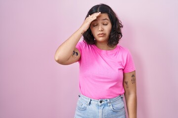 Young hispanic woman standing over pink background worried and stressed about a problem with hand on forehead, nervous and anxious for crisis