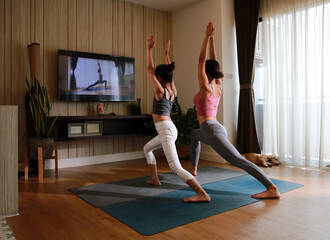 Healthy Family, Mom and daughter learning Yoga online at home,  Yoga practice at home via online training