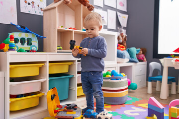 Adorable caucasian boy standing with relaxed expression playing at kindergarten