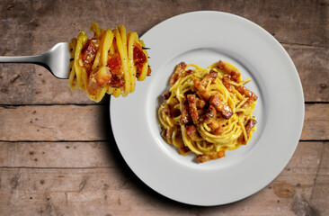 Top view of plate with spaghetti carbonara on wooden table