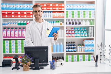 Young caucasian man pharmacist using touchpad and computer at pharmacy