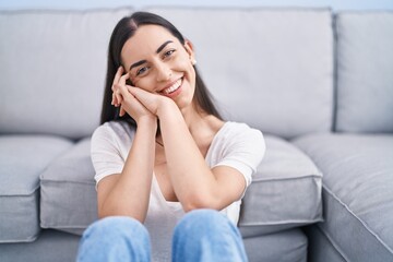 Young hispanic woman smiling confident sitting on floor at home