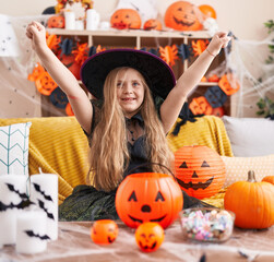 Adorable blonde girl wearing witch costume with winner expression at home