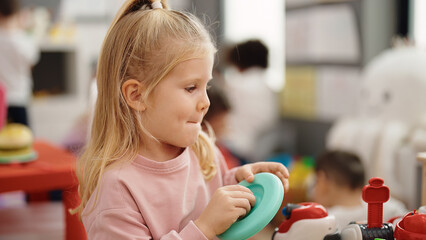 Adorable blonde girl smiling confident playing at kindergarten