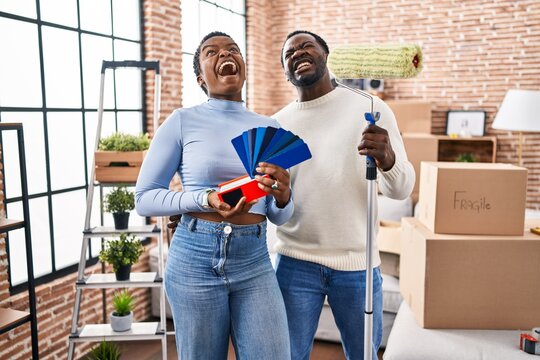 Young african american couple moving to a new home choosing walls color angry and mad screaming frustrated and furious, shouting with anger looking up.