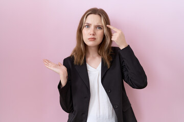 Young caucasian business woman wearing black jacket confused and annoyed with open palm showing...