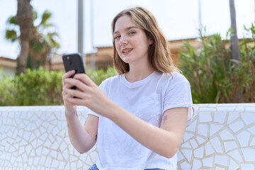 Young caucasian woman smiling confident using smartphone at park