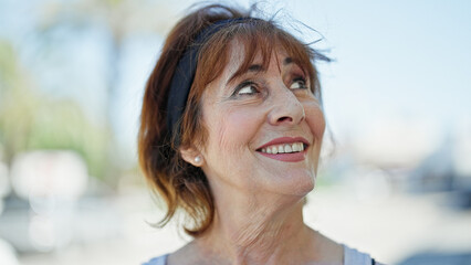 Middle age woman smiling confident looking to the sky at street