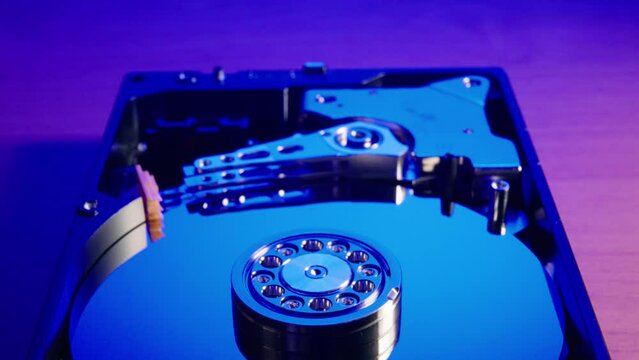 Closeup of a hard disk drive mechanism on blurred background illuminated with blue and purple lights