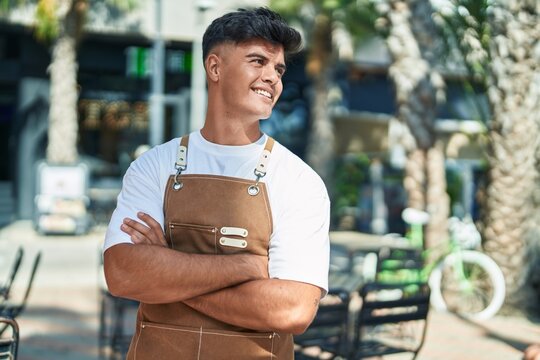 Young hispanic man waiter smiling confident standing with arms crossed gesture at coffee shop terrace