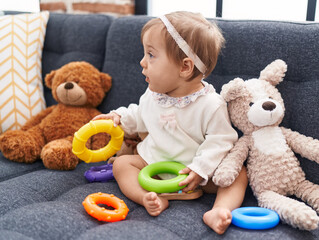 Adorable caucasian baby playing with hoops game sitting on sofa at home