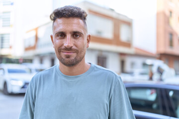 Young hispanic man smiling confident standing at street