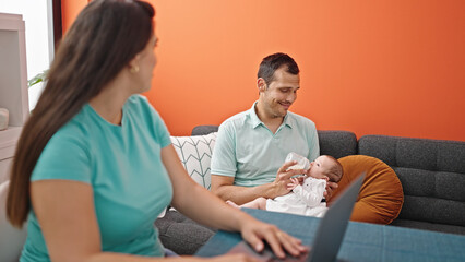 Young mother with her family using laptop at home