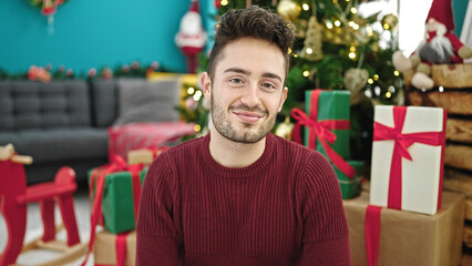 Young hispanic man celebrating christmas smiling at home