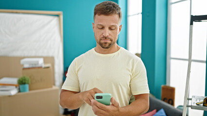 Young man using smartphone standing with serious face at new home
