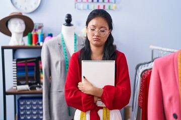 Asian young woman dressmaker standing by manikin depressed and worry for distress, crying angry and afraid. sad expression.