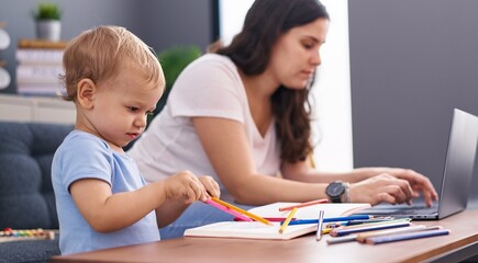 Fototapeta premium Mother and son drawing on notebook using laptop at home