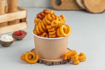 Closeup of a white cup with Curly Fries with sauces