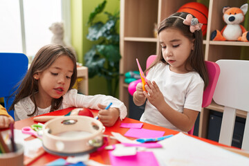 Adorable girls student cutting paper drawing on paper at kindergarten