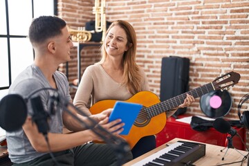 Man and woman musicians having classic guitar lesson using touchpad at music studio