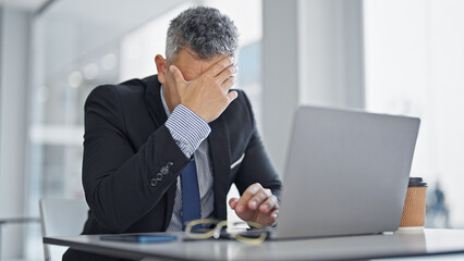 Young hispanic man business worker using laptop stressed at office