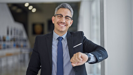 Fototapeta premium Young hispanic man business worker smiling confident looking watch at office