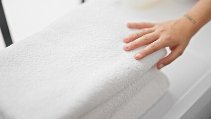 Young beautiful hispanic woman touching folded towels at laundry room