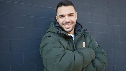 Fototapeta premium Young hispanic man smiling confident standing with arms crossed gesture over isolated black background