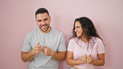 Man and woman couple standing together dancing over isolated pink background