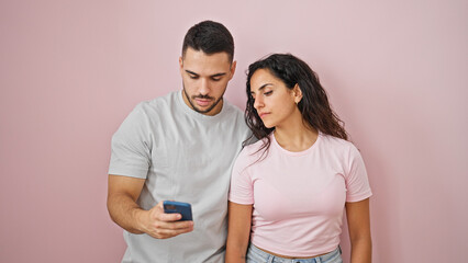 Naklejka premium Man and woman couple using smartphone over isolated pink background