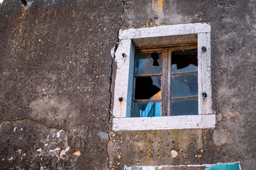 Broken window in an old beaten and robbed building in the city, old historical building