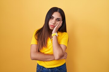 Young arab woman standing over yellow background thinking looking tired and bored with depression problems with crossed arms.