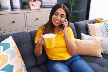 Young beautiful arab woman talking on smartphone drinking coffee at home