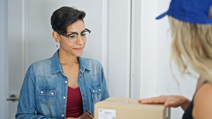 Young beautiful hispanic woman opening door receiving package at home