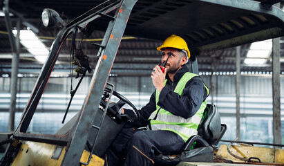 Fototapeta na wymiar Industrious Engineer Operating Forklift in Warehouse. Efficient Forklift Driving in Factory. Engineer is working and maintaining in the factory.