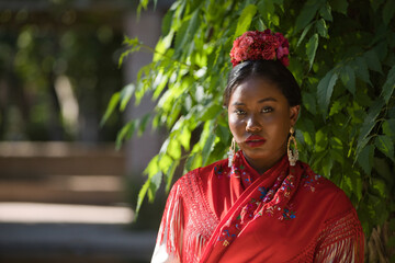 Portrait of young black and South American woman in a beige gypsy flamenco suit and red shawl,...