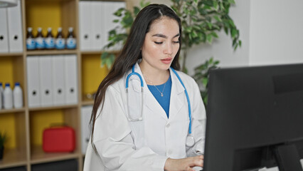 Young beautiful hispanic woman doctor using computer working at the clinic