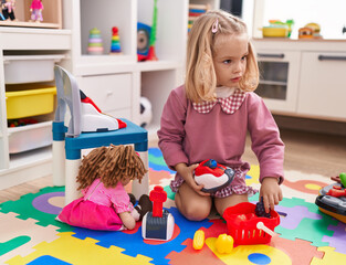 Adorable blonde girl playing supermarket toys sitting on floor at kindergarten