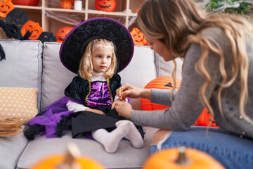 Adorable blonde girl sitting on sofa having halloween make up on hand at home