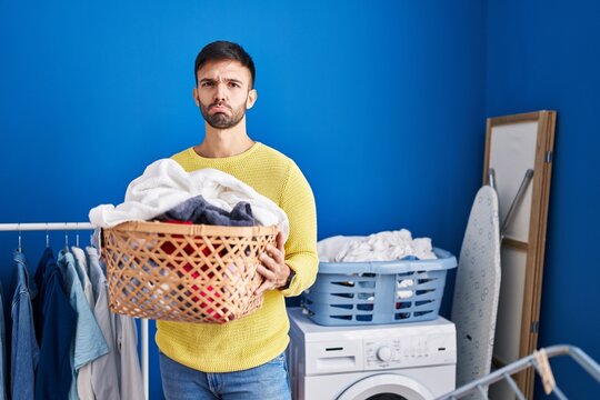Hispanic man holding laundry basket depressed and worry for distress, crying angry and afraid. sad expression.