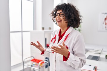 Young beautiful hispanic woman doctor smiling confident speaking at clinic