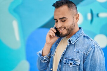 Young hispanic man smiling confident talking on the smartphone at street