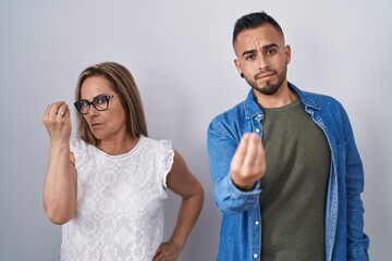 Hispanic mother and son standing together doing italian gesture with hand and fingers confident expression